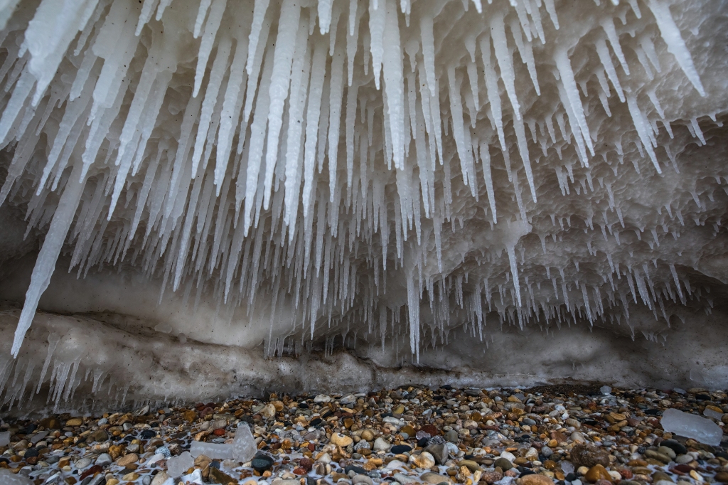 Icicles hang from the ceiling of a small opening in the bottom of an ice shelf.